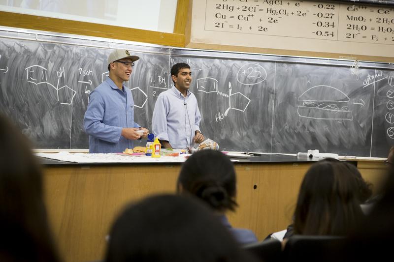Two people standing at the front of a lecture hall