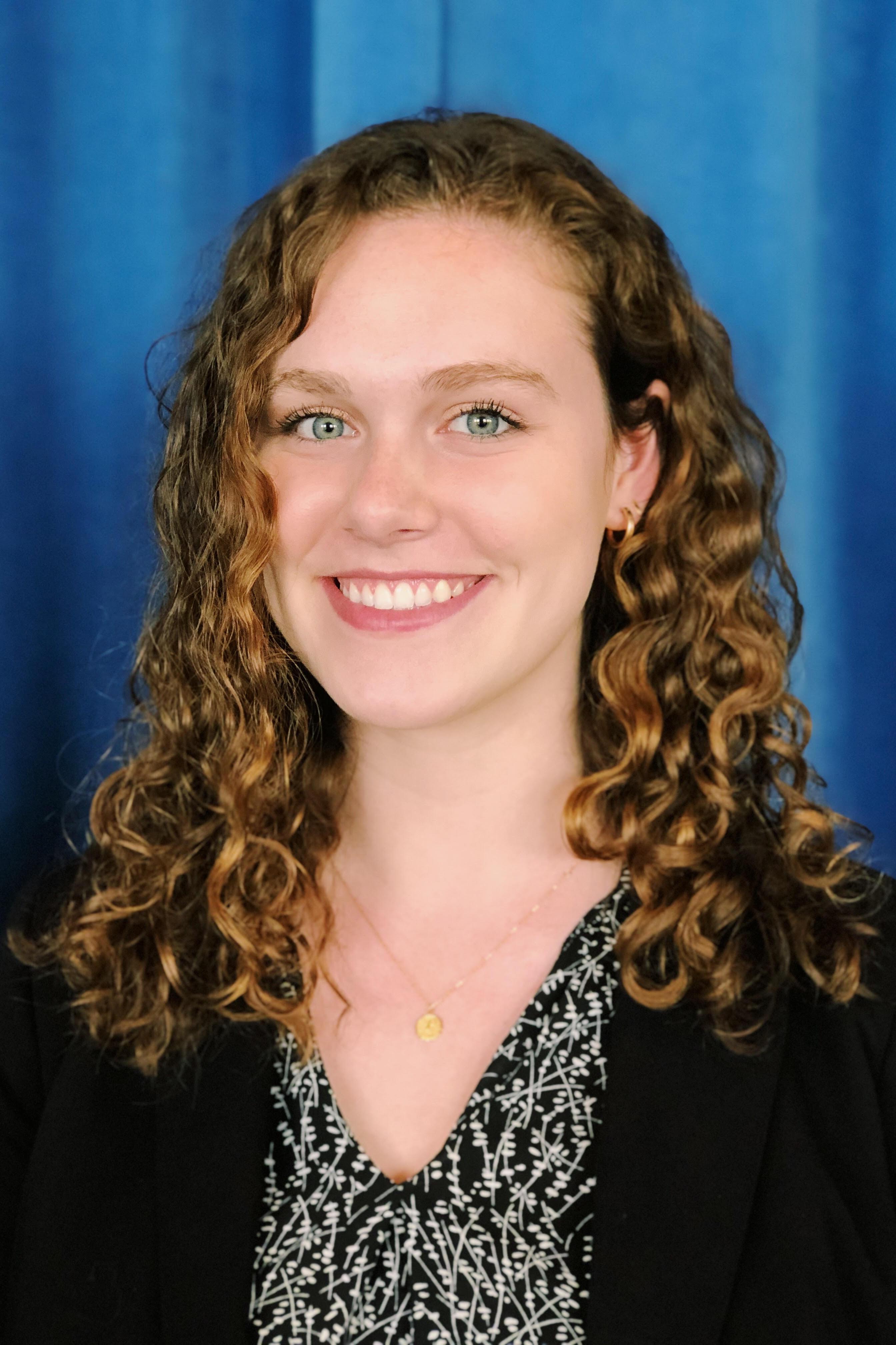 Picture of Emily Gibson standing in front of a blue curtain