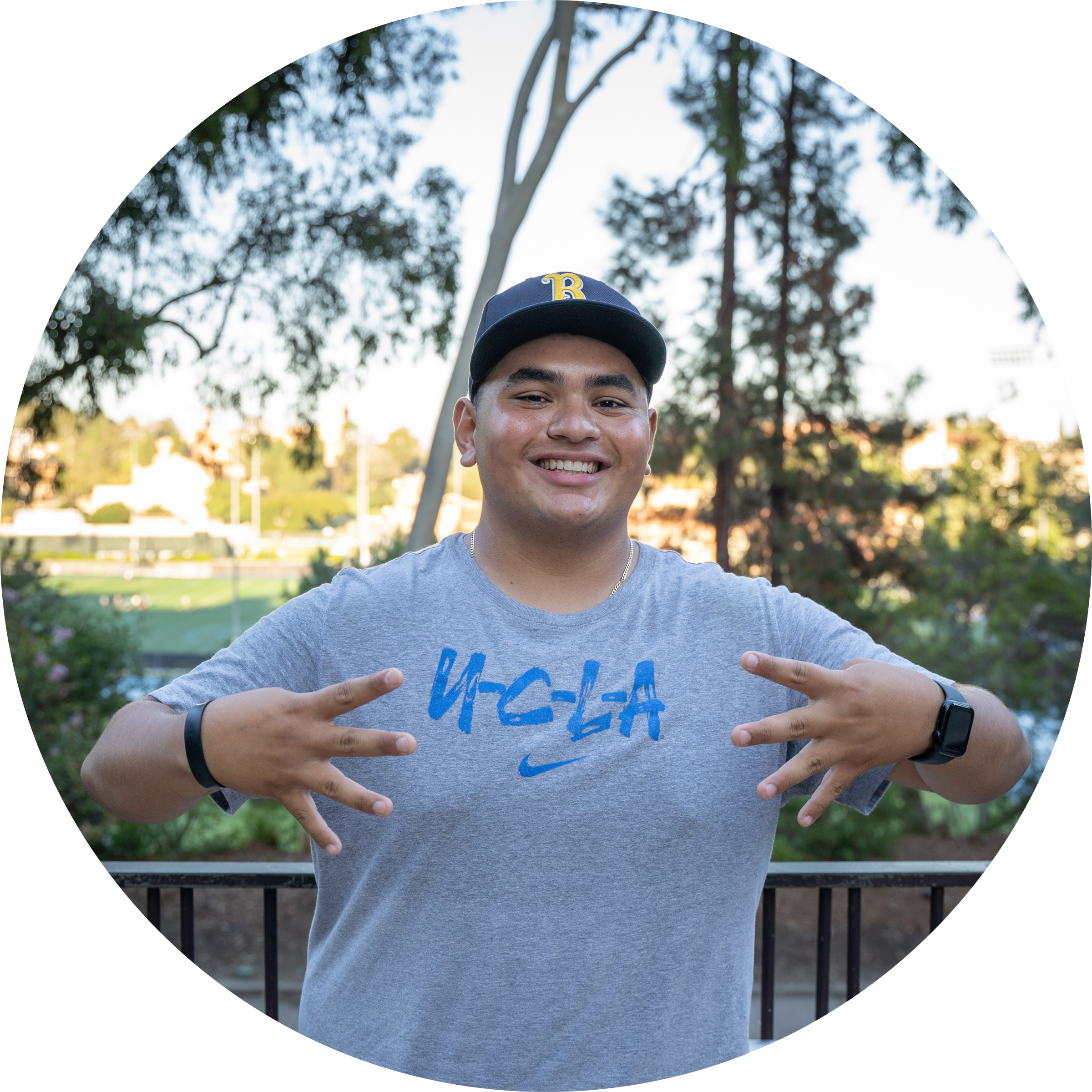 UCLA Student posing with Bruin gear on displaying 4's up.