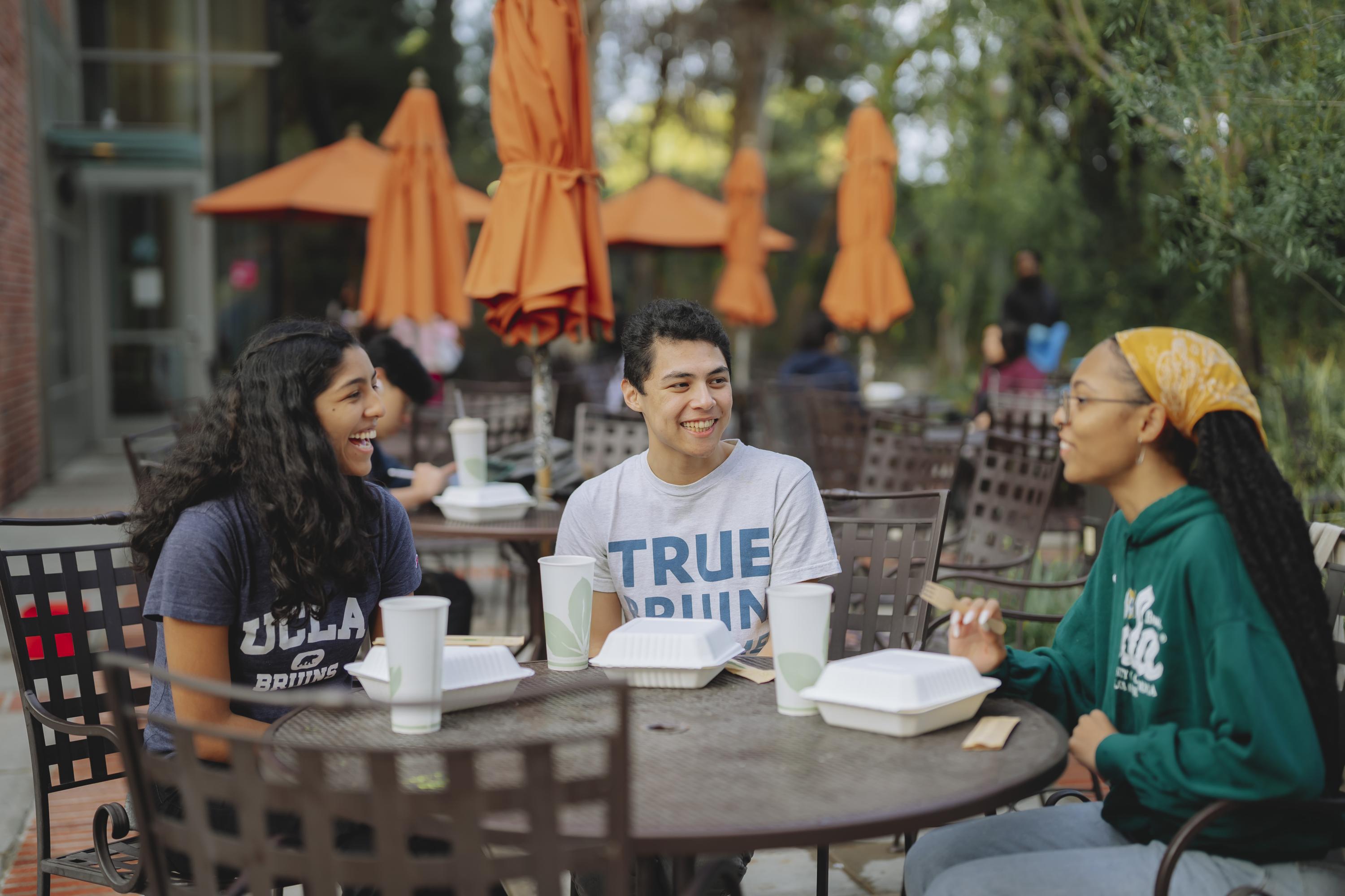 three students eating at an outdoor table