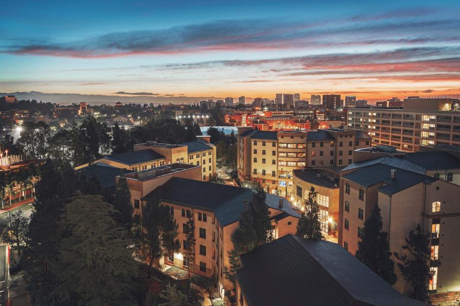 A picture of the De Neve Dykstra Residential Community, at sunset time. The buildings cover the bottom two thirds of the photo, with a sunset streaked sky covering the top, fading to a dark blue